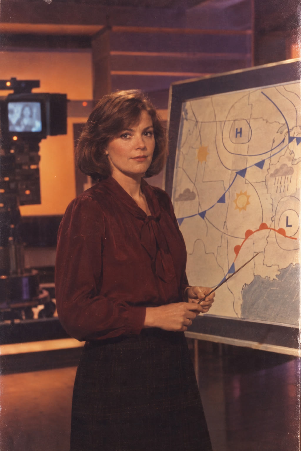 Marian Coil, a brown-haired meteorologist beside a weather map